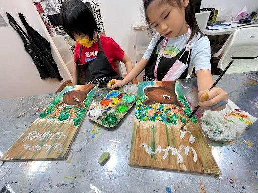Children painting festive decorations at a workshop table.