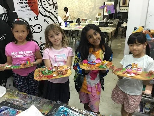 Children showing colourful handmade clay projects.