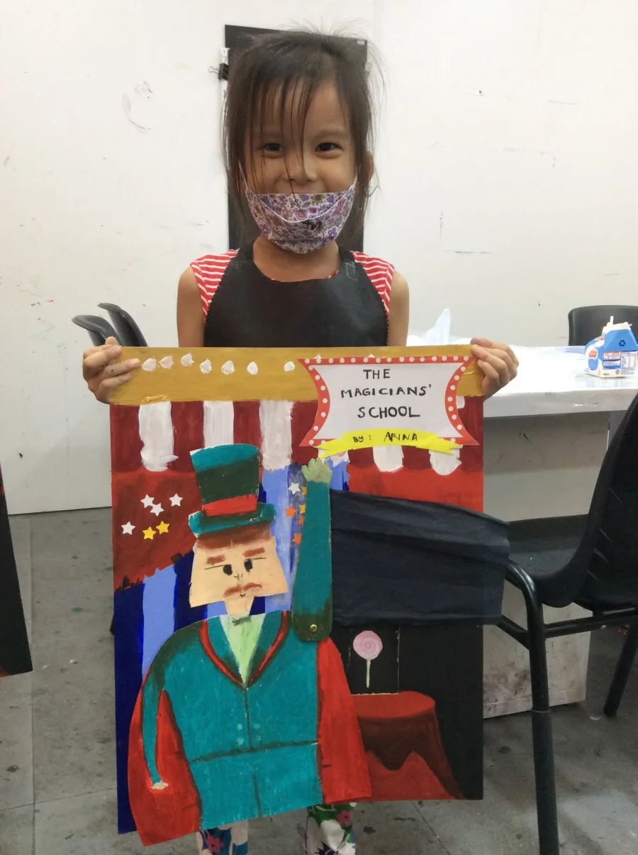 Child holding a large magician-themed collage with a top hat and stage curtains.