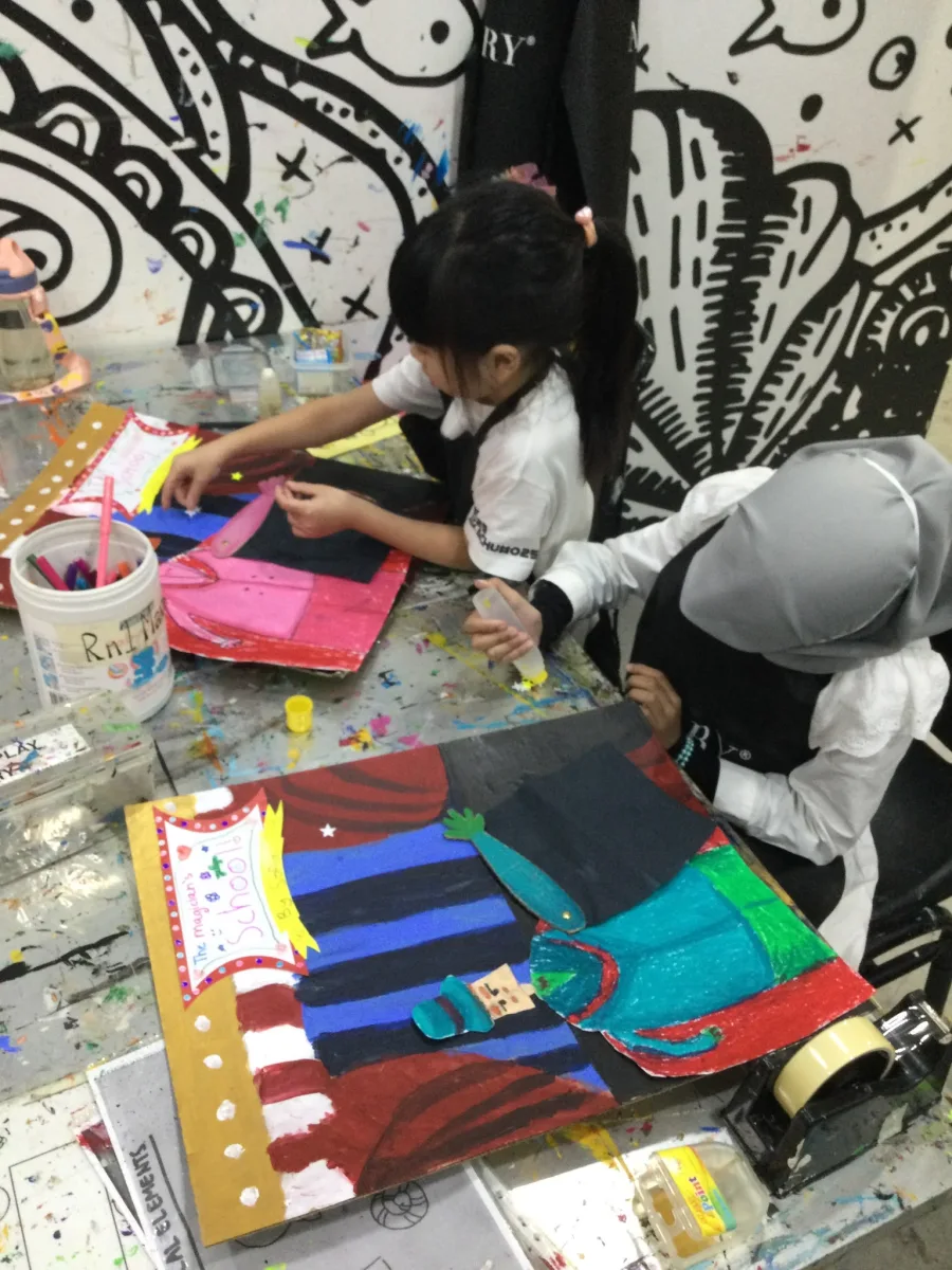 Children adding paper shapes and details to magician collages.