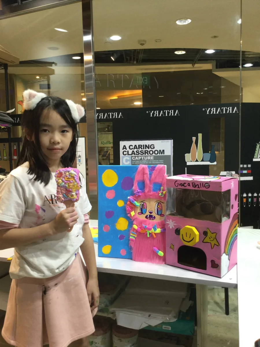 Pink furry portrait and handmade capsule machine beside their maker.